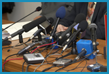 Table covered with a variety of microphones and recording devices.
