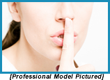 Woman with index finger poised before her pursed lips indicating "shhh" (Staged with professional model).