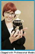 Red-headed woman with black glasses holding a trophy (staged with a professional model).